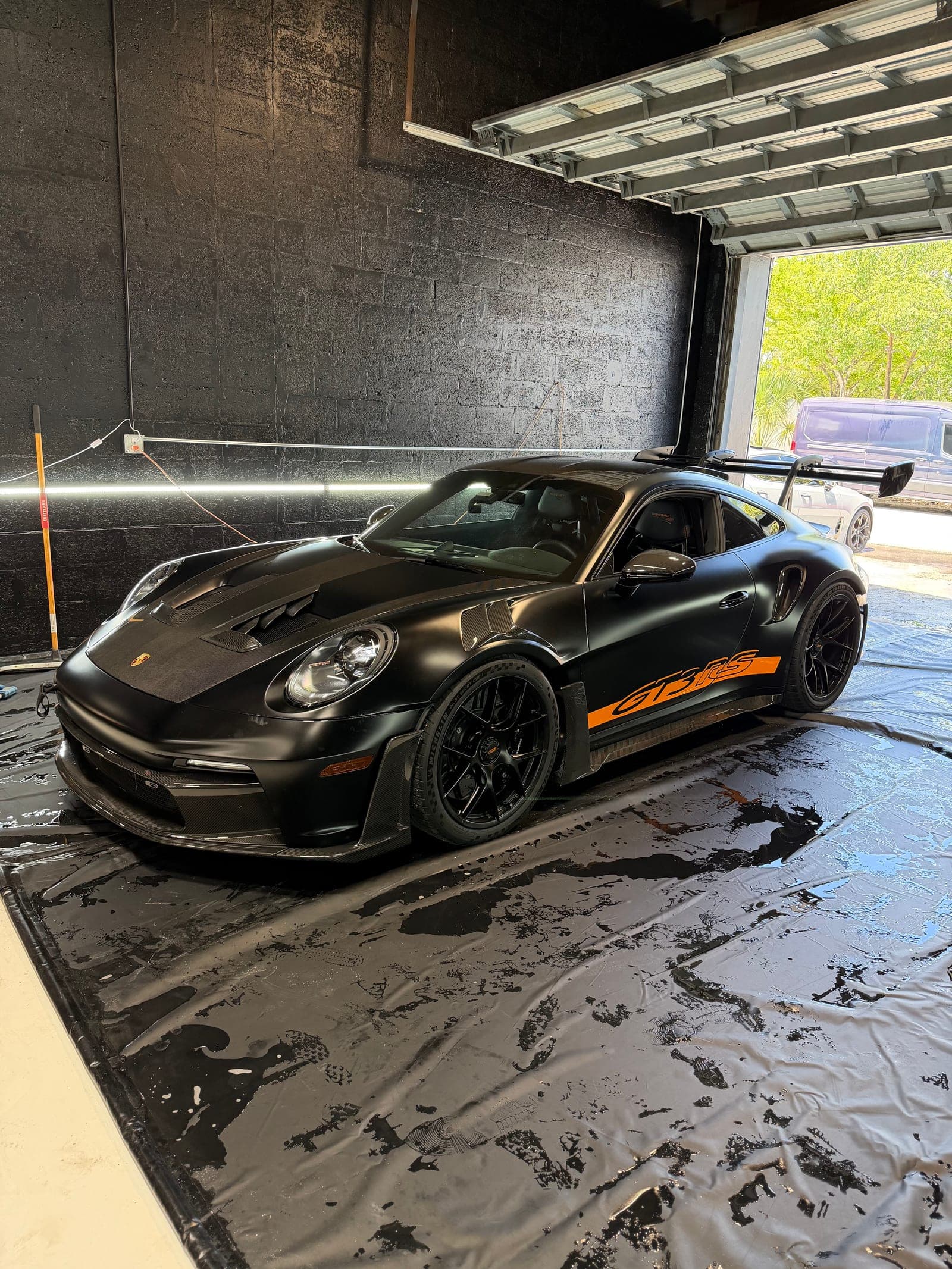 Matte black Porsche 911 GT3 RS with orange accents inside the Sunflo Fort Lauderdale bay after a full exterior detail